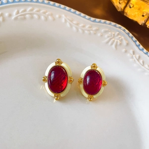 Detail of vintage oval red gemstone earrings with white enamel and gold metal accents