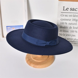 Detail of navy wool felt fedora with ribbon band on wooden stand in studio