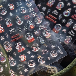 Macro shot of 3D embossed Christmas nail stickers with Santa and snow globe patterns