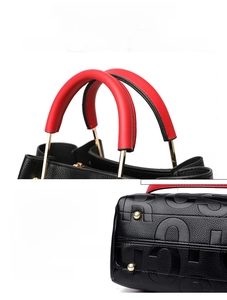 Detail view of black pebbled leather tote with red handle and gold hardware studs