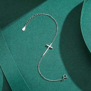 Minimalist S925 sterling silver cross bracelet with polished finish on a dark green background