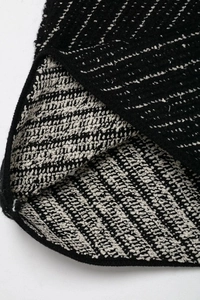 Close-up of black and white woven tweed fabric texture on a knit two-piece set