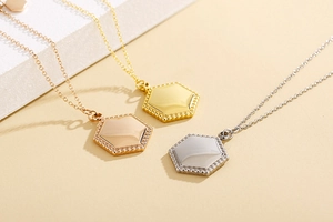 Three minimalist hexagonal pendants in gold, rose gold, and silver on delicate cable chains
