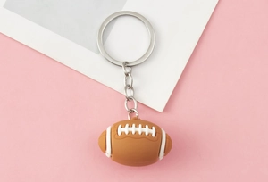 Detail of a brown American football keychain with white stitching and silver metal ring