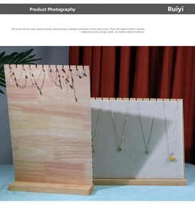 Macro detail of wooden jewelry display board with grey velvet slots and hooks for necklaces