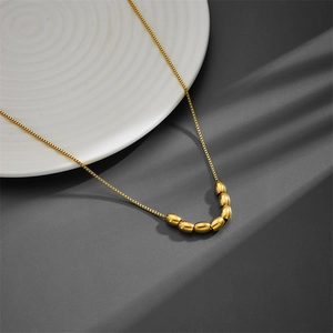 Detailed view of titanium gold box chain necklace with elegant beads on a ceramic plate