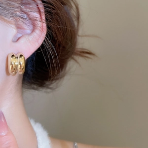 Detail view of double layer gold huggie earrings with a high-polished mirror finish