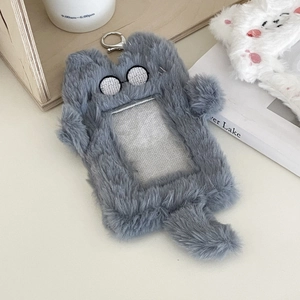Detail of plush grey cat card holder with metal clip on a cozy desk background