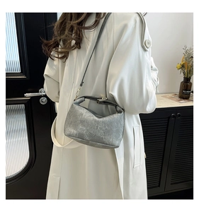Fashionable grey shoulder bag with vintage texture shown on person wearing beige coat