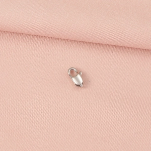 Macro shot of a silver lobster clasp on pink fabric for jewelry making DIY