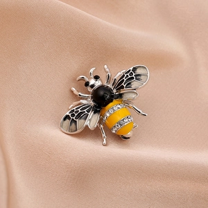 Cute bee brooch with pearls and zircons on champagne silk fabric macro view