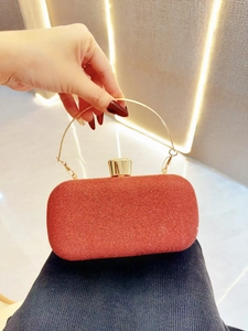 Detail of red glitter evening clutch bag with round gold handle and metal clasp