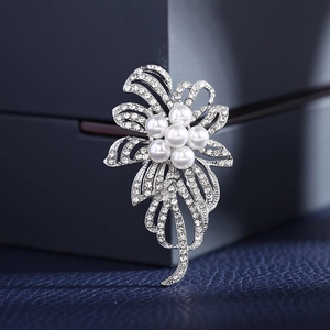 Broche florale argentée avec perles blanches et strass sur support bleu chic