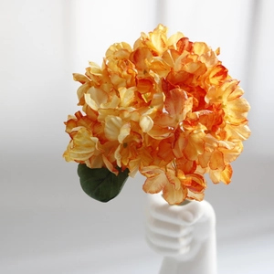 Artistic detail of orange hydrangea petals in a creative hand-shaped ceramic vase