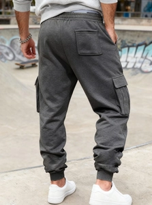 Detail of dark grey cargo joggers featuring side flap pockets and elastic cuffs