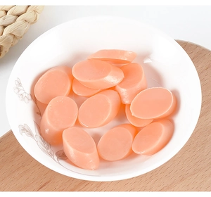 Close-up of pink oval faux food sausage slices in a white floral patterned ceramic bowl