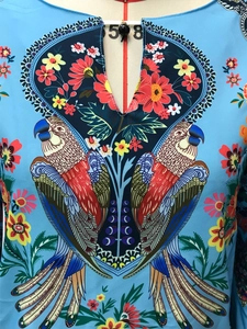 Détail du col en V avec boutons décoratifs et imprimé floral numérique perroquet vif