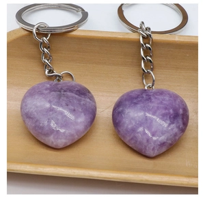 Close-up of dual heart-shaped natural purple amethyst keychains on a wooden tray