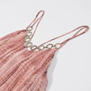 Dettaglio vestito da donna con colletto a catena in metallo e tessuto tie-dye rosa