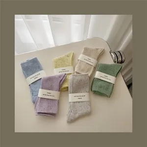 Detailed knit texture of six pastel colored confetti socks with elegant paper wrapping