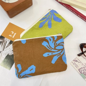 Detail of floral canvas pouches with silver zippers on a styled tabletop background