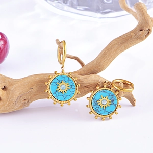 Detail of gold hoop earrings featuring turquoise discs and celestial sun patterns