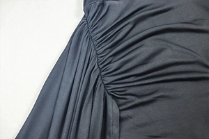 Detailed close-up of ruched side seams and pleated fabric on black sleeveless dress