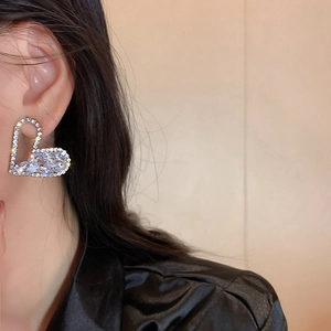 Macro detail of silver heart earrings with sparkling cubic zirconia on female model