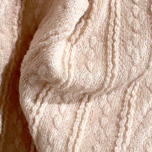 Detailed macro shot of beige knit fabric texture with soft wavy ribbed patterns