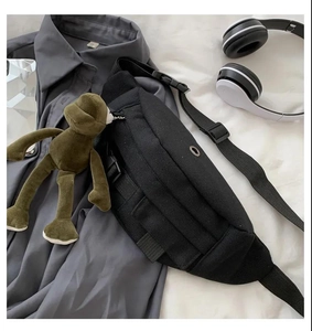Flat lay of black canvas chest bag with adjustable strap and casual accessories