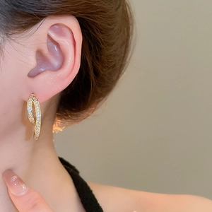 Close-up of 18k gold plated U-shaped earrings with zircon crystals on model ear