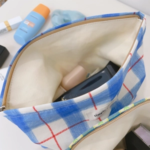 Detail view of a blue checkered fabric makeup bag with zipper and inner lining storage