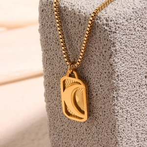 Macro detail of 18K gold plated rectangular pendant with engraved crescent moon and sun