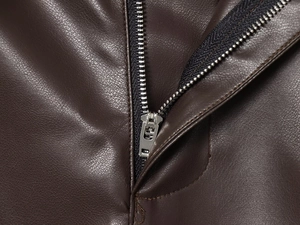 Dettaglio della cerniera in metallo e della trama della pelle marrone sui pantaloni