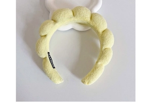 Close-up of pale yellow cloud sponge headband featuring soft terry cloth and brand label