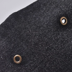 Close-up of vintage washed denim fabric with metallic air eyelets and twill texture