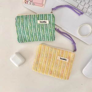 Close-up of small knitted cosmetic bags in green and yellow with zip and purple wristlet