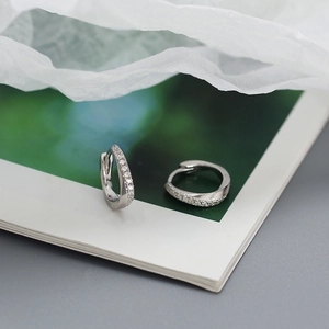 Close-up of irregular silver pavé diamond hoop earrings on minimalist artistic background