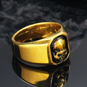 Macro shot of polished gold punk ring featuring detailed black skull relief and reflection