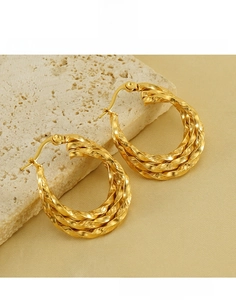 Close-up of twisted gold layered earrings on stone to show 18K plating and steel texture