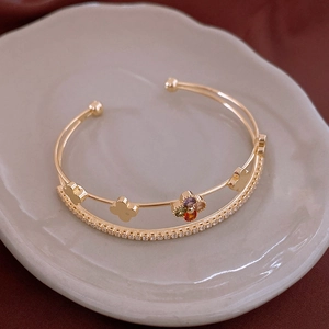 Detailed macro of gold double-layer clover bangle with colorful zircon and micro-pave stones