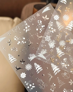 Détail des stickers ongles Noël en relief 3D avec des motifs de flocons dorés et argentés