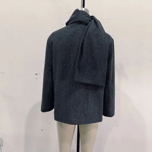 Macro detail of dark grey wool blend coat featuring integrated scarf hood and buttons