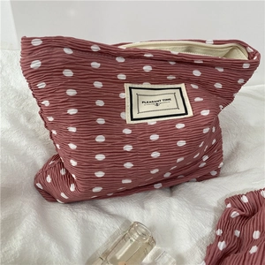Detailed macro view of pink ruffled fabric chiffon cosmetic bag with white polka dots