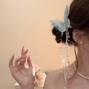 Detail of blue butterfly hair clip with pearl tassels and shimmering mesh wings