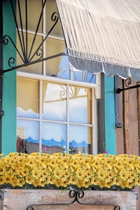 Detailed close-up of yellow artificial flowers in a rustic wooden planter box for decor