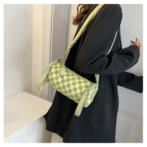 Detail of light green checkered cylinder crossbody bag with stylish wide shoulder strap