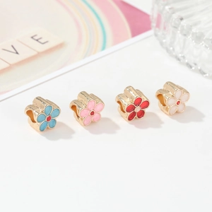 Detailed close-up of four enamel flower charms in blue, pink, red and white with gold trim