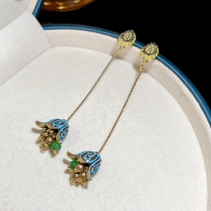 Macro shot of vintage gold earrings with blue enamel flowers and green bead tassels