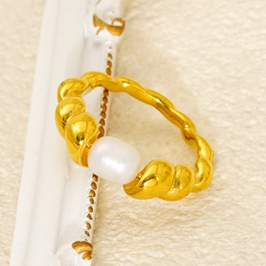 Detail of a gold twisted croissant ring featuring a lustrous white oval pearl inlay